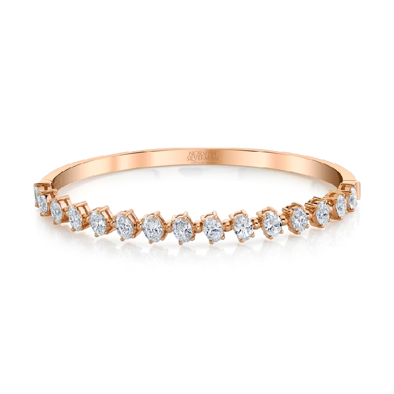 Oval-cut Diamonds set in 4-prong pink gold bangle bracelet.